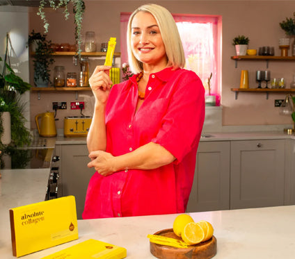Image of Absoluter Holly holding an Absolute Collagen Sachet in her kitchen.