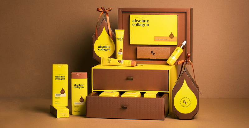 Image of a collection of Absolute Collagen products, including haircare, the collagen supplement and collagen boosting serum. Displayed in gifting packaging. 